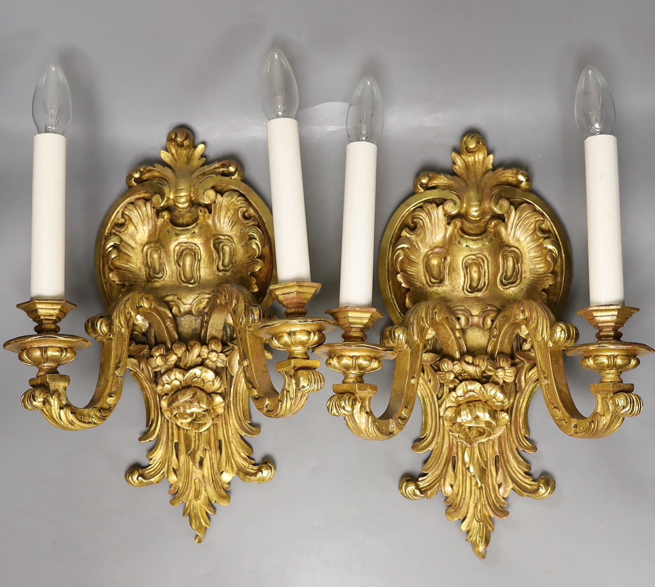 A pair of gilt carved wooden two branch wall sconces, 42 cms high.